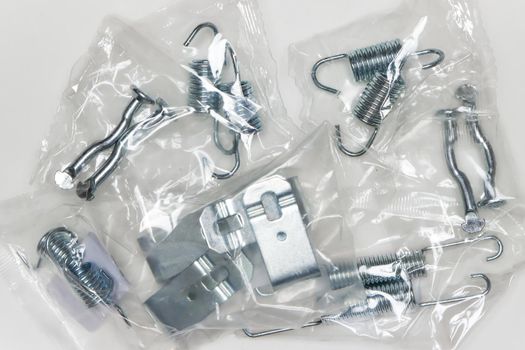 A set of metal components in the package, parts for car repair. A set of spare parts for servicing vehicle calipers. Details on white background, copy space available.
