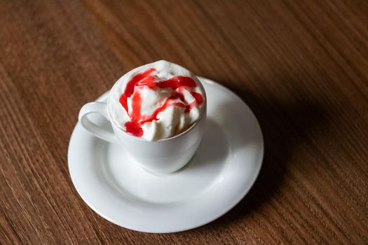 Cup of coffee with cream and jam closeup, top view
