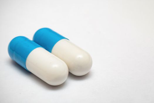 Two white blue medicine pills close up, on gray background