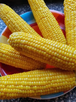 Boiled juicy yellow corn in a plate on the table close-up.