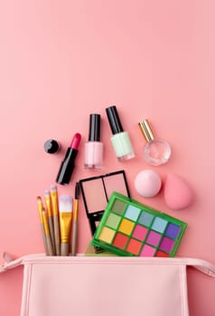 Bright summer eyeshadow palette and makeup products in pink cosmetic bag on pink background. Makeup cosmetics. Colorful colors. Place for text. Flat lay. Top view. layout