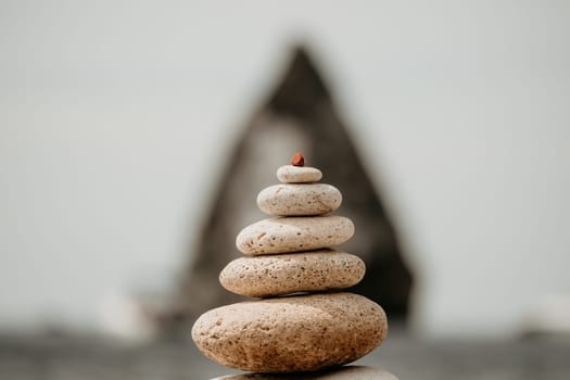 Pyramid stones on the seashore with warm sunset on the sea background. Happy holidays. Pebble beach, calm sea, travel destination. Concept of happy vacation on the sea, meditation, spa, calmness.