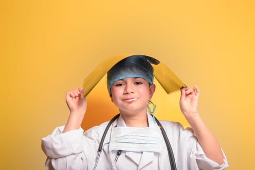 Smiling child boy doctor on yellow background. Male doc in white medical gown. Healthcare health medicine concept. Mock up copy space