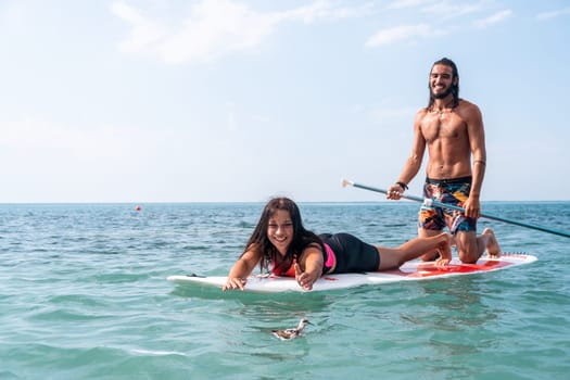Silhouette of woman standing, surfing on SUP board, confident paddling through water surface. Idyllic sunset or sunrise. Sports active lifestyle at sea or river.