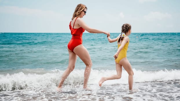 Happy loving family mother and daughter having fun together on the beach. Mum playing with her kid in holiday vacation next to the ocean - Family lifestyle and love concept.