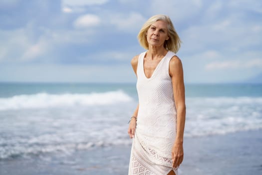 Mature female walking on the beach. Elderly woman enjoying her retirement at a seaside location.