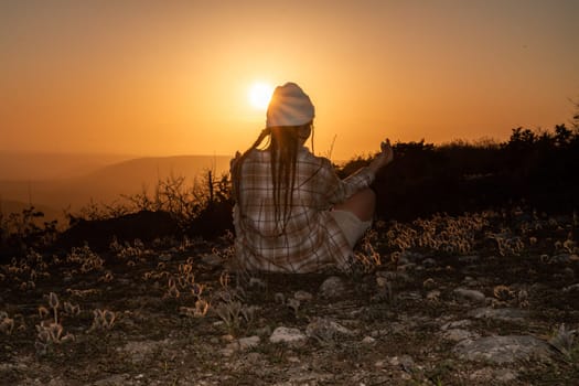 Woman tourist on top of sunrise mountain. The girl salutes the sun, wearing a jacket, white hat and white jeans. Conceptual design