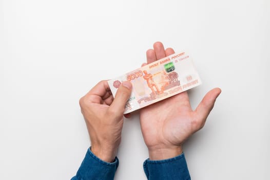 Human caucasian hands hold five thousand rubles on a white background, top view. The concept of finance, poverty, poor or rich, successful, earning.