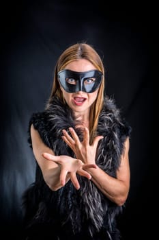 Woman in black mask performing in studio against black background