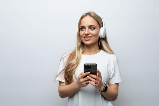blogger girl with a headset on her head and a phone in her hands on a white background.