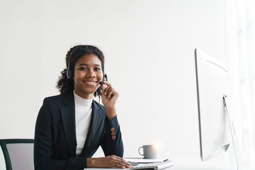 Portrait of happy smiling female customer support phone operator at workplace. Smiling beautiful African American woman working in call center.