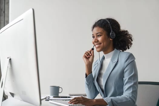 Portrait of happy smiling female customer support phone operator at workplace. Smiling beautiful African American woman working in call center.