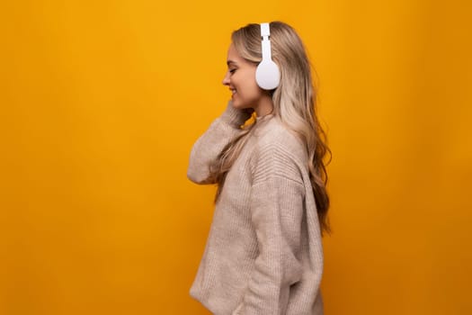 girl attentively listens to a podcast in headphones on a yellow background.