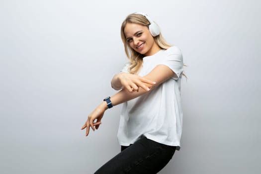 blond girl in headphones enjoys music on a white background.