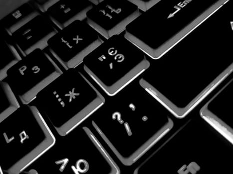 Computer keyboard black and white backlit close up.