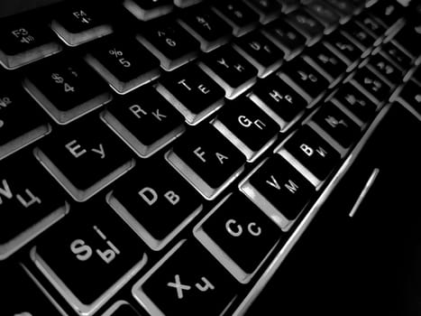 Computer keyboard black and white backlit close up.