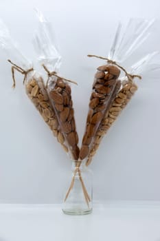 Almonds and peanuts in a transparent package on a gray-white background.