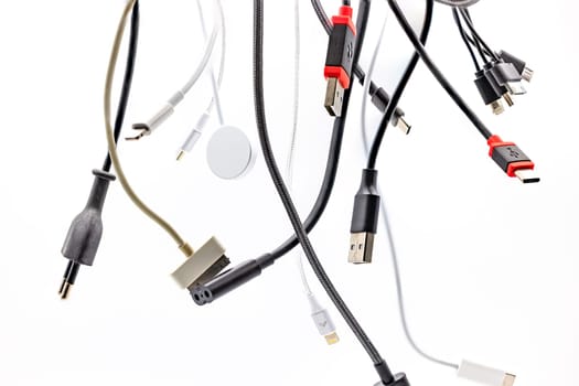 Chaos and confusion with plugs, sockets and USB cables isolated against a white background with focus stacking