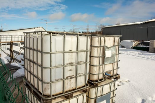a plastic cubic water container protected by a metal grid. Plastic tanks for storage and transportation of chemical liquids.