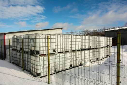 a plastic cubic water container protected by a metal grid. Plastic tanks for storage and transportation of chemical liquids.