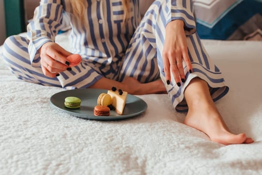 a woman in the morning drinks coffee and eats sweets cheesecake sweet macaroni . breakfast in bed concept