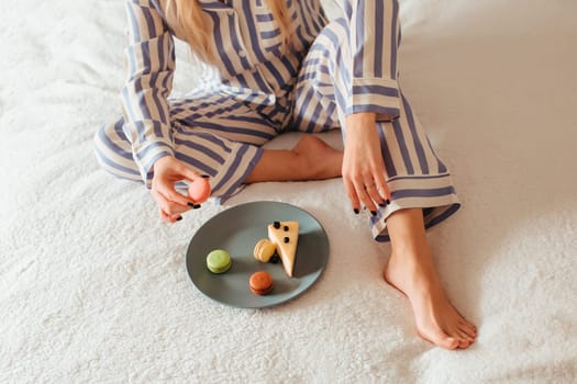 a woman in the morning drinks coffee and eats sweets cheesecake sweet macaroni . breakfast in bed concept