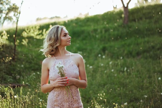 a woman at sunset in a field of dandelions in a pink dress . the concept is not allergic .