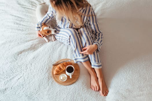 morning breakfast in bed croissant and coffee. next to her is a woman in pyjamas . top view