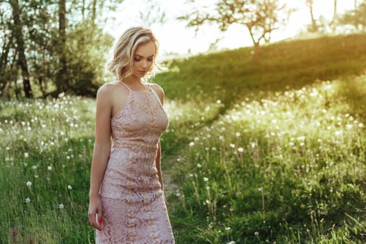 a woman at sunset in a field of dandelions in a pink dress . the concept is not allergic .