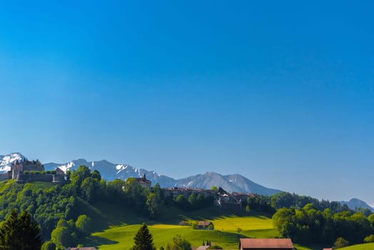 Castle of Gruyeres among forest and greend meadows in Haut-Intyamon, Gruyere, Fribourg, Switzerland.