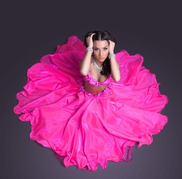 Full length portrait of beautiful dancer in pink costume sitting on floor look at camera