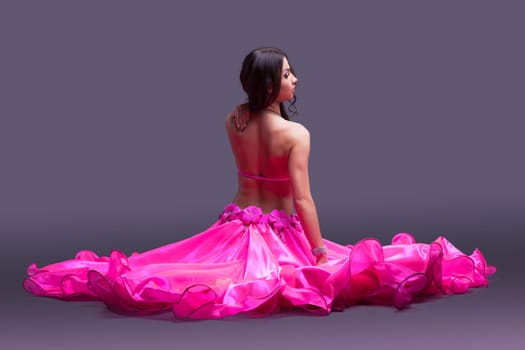 Studio portrait of dancer in pink costume sitting on floor