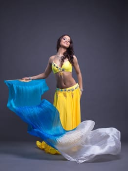 Full length portrait of pretty dancer in yellow oriental costume with veer