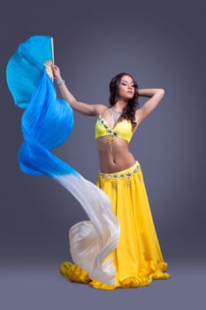 Full length portrait of pretty dancer in yellow oriental costume with veer