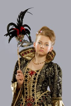 Full length portrait of young girl posing in carnival costume like queen with mask