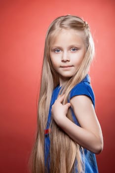 Portrait of pretty blonde girl in fashion dress on red background