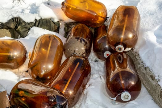 a large dark plastic bottle of juice or beer in the snow