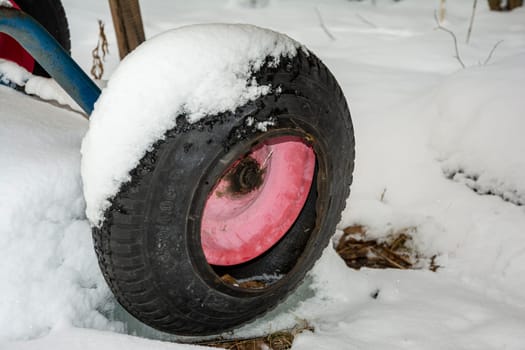 a deflated, damaged wheel from a garden wheelbarrow in the snow. High quality photo