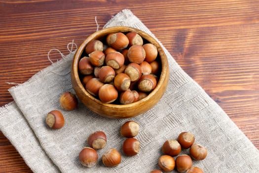Heap or stack of hazelnut set, on dark wooden table.