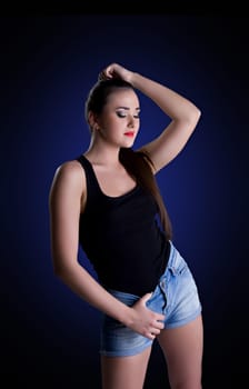 Studio portrait of young brunette woman in denim shorts and black top