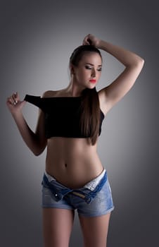 Studio portrait of pretty young woman in denim shorts and undress black top