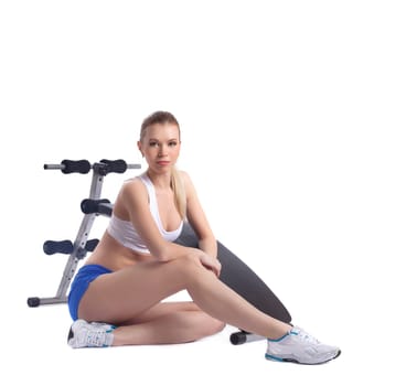 Young blonde woman near exerciser. Isolated on white