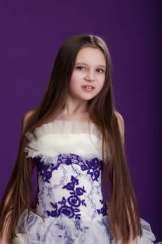 Portrait of beautiful little girl with long hair, on purple background
