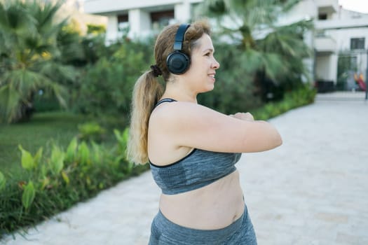 Young pretty smiling plus size woman in sporty top and leggings doing sport in summer outdoor