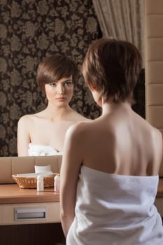 Slender brunette in towel posing near mirror, close-up