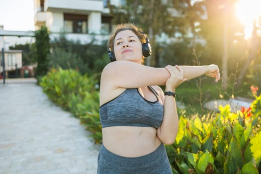 Young pretty smiling plus size woman in sporty top and leggings doing sport in summer outdoor