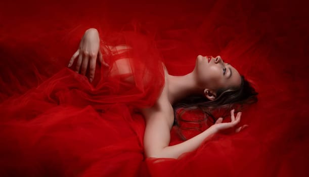 portrait of a beautiful girl lying in the background in a red transparent fabric with a bright red background copy paste