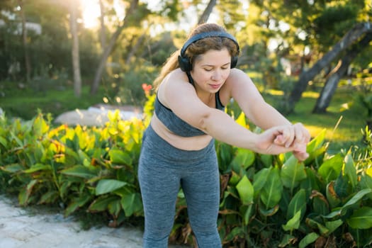 Young pretty smiling plus size woman in sporty top and leggings doing sport in summer outdoor