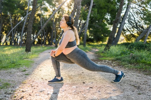 Young pretty smiling plus size woman in sporty top and leggings doing sport in summer outdoor