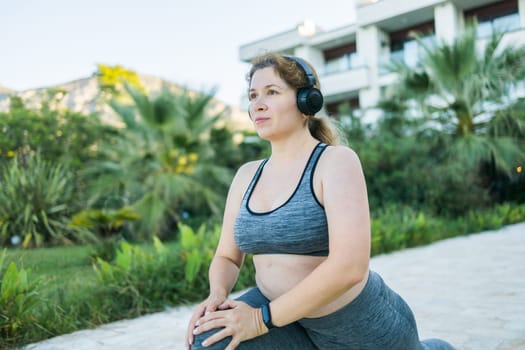 Young pretty smiling plus size woman in sporty top and leggings doing sport in summer outdoor